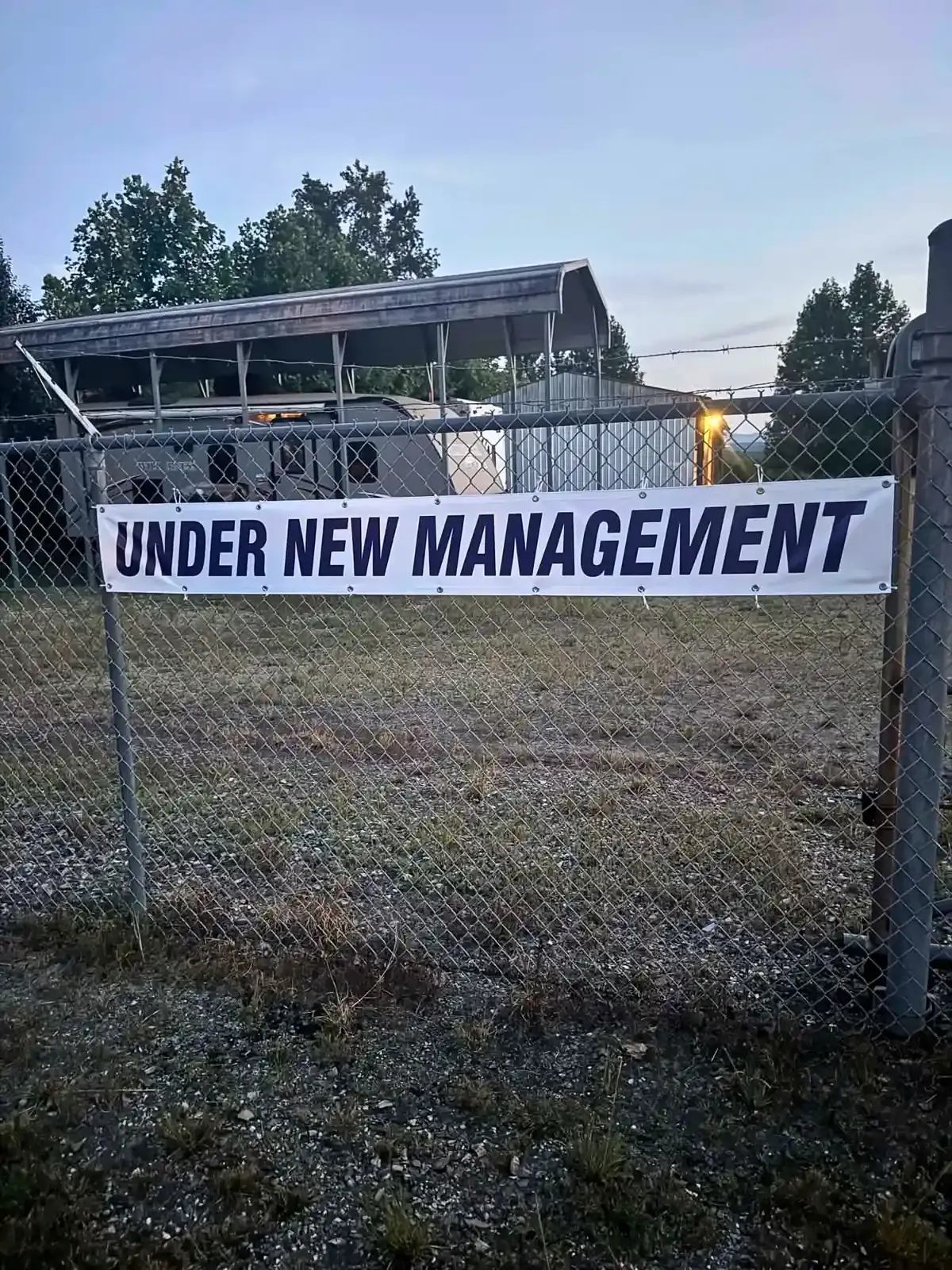 Chain link fence with an "Under New Management" banner